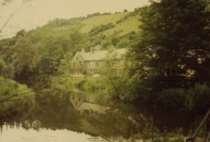 Colour photo of Litton Mill with hills in the background and the river in the foreground