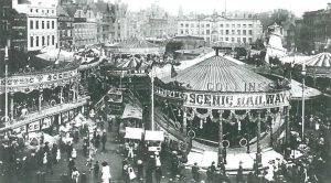 Photo of the crowds at Goose Fair showing two rides, including a 'scenic railway'