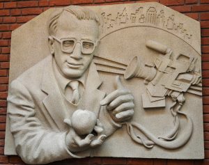 Frieze of Woody Allen holding an apple next to a TV camera, made of lightweight resin but meant to look like stone