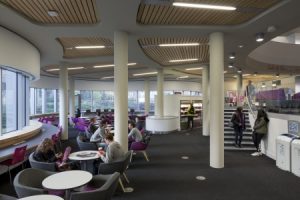 Photograph of students sitting at tables in the café area in George Green Library