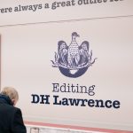 Man looking in exhibition case under the 'Editing D H Lawrence' title on the wall.