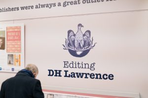 Man looking in exhibition case under the 'Editing D H Lawrence' title on the wall.