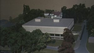 Photograph of the architect's model of the University Library. The model includes trees, the road, and tiny people. It also includes a model of the Hemsley Building.