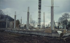 Photograph of foundations of a building laid into mud with several concrete columns rising up. 