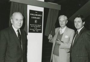 Photograph of three men next to a plaque and a small curtain. The curtain has been opened by the centre man. The plaque reads, "The Hallward Library, Bertrand Leslie Hallward, First Vice-Chancellor of the University of Nottingham, 1948-1965".