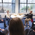 Photo of staff and feminists seated in a circle having a discussion.