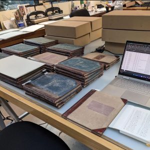 Piles of bound volumes and archive boxes on a table