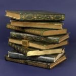 Image of all 8 volumes of the 4th Duke of Newcastle's Diaries in a stack. They are small green volumes with gold detail.