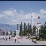 A colour photograph of Skanderbeg Square, Tirana showing trees, monuments and buildings.
