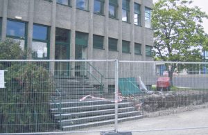 Photograph of the steps leading up to the library building. A construction fence blocks the path.