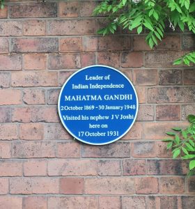 Photograph showing a blue commemorative plaque on a brick wall