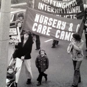 Rosemary marching pushing a push chair and holding a placard featuring one of her designs.