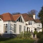 Colour photograph of a white building surrounded by greenery.