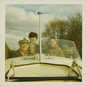 A woman wearing a captain's hat sailing a boat with friends. 