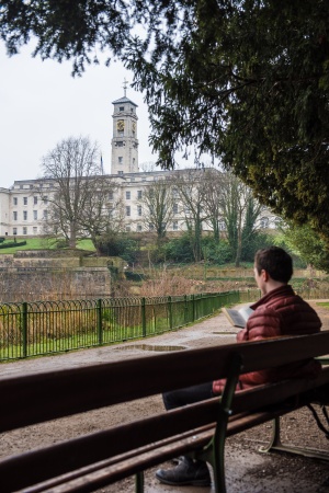 University Nottingham stock image of a man sitting on a bench near the lake and Trent Building
