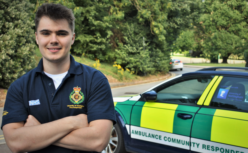 James Conlan smiling at the camera next to a community ambulance