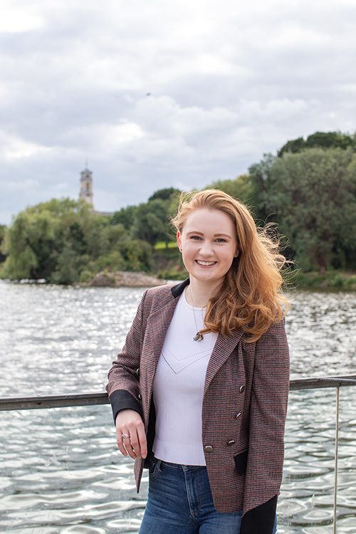 Julia Cox smiling at the camera in front of the University of Nottingham lake