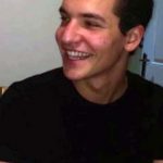 Roei in a black t-shirt smiling at a person out of view of the camera