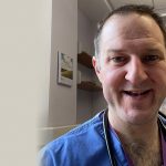 Professor Adam Gordon smiling at the camera in his medical scrubs