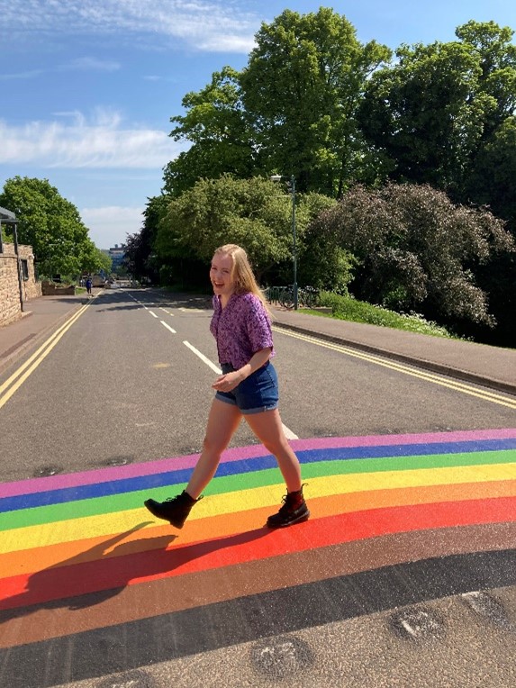 Imogen Hullis smiling and walking across the Pride crossing