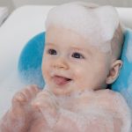 A baby covered in soap suds in a bath