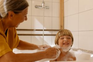 Mother washing her young son in the bath.