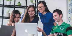 A group of four international students looking at a laptop