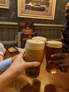 Image of three pint glasses raising a toast in the pub