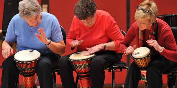 Older people taking part in a drumming workshop