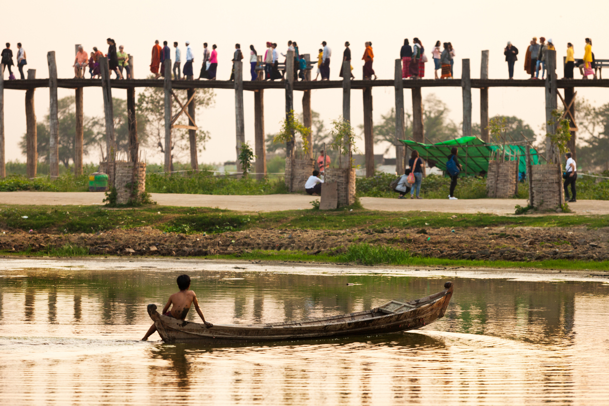 A boy in a small boat and people on a bridge in Myanmar, one of the countries where projects are eligible for GCRF funding