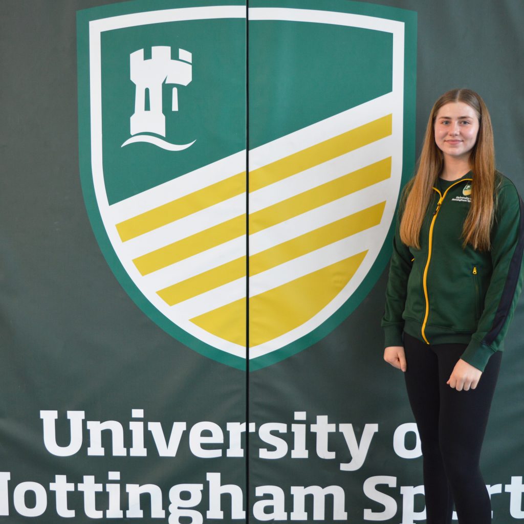 Rachel Ellis in front of the University of Nottingham Sport logo