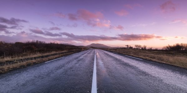 An image of a road leading in to the distance with a sunset
