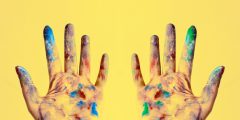 creative paint-stained hands on a yellow background.