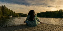 woman meditating and relaxing in front of lake