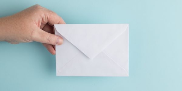 a hand holding a plain white envelope