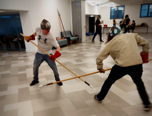 two men wearing medieval helmets duel with spears