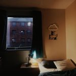 Dimly lit bedroom with a cloud shaped light and bedroom sticker that reads "be kind"