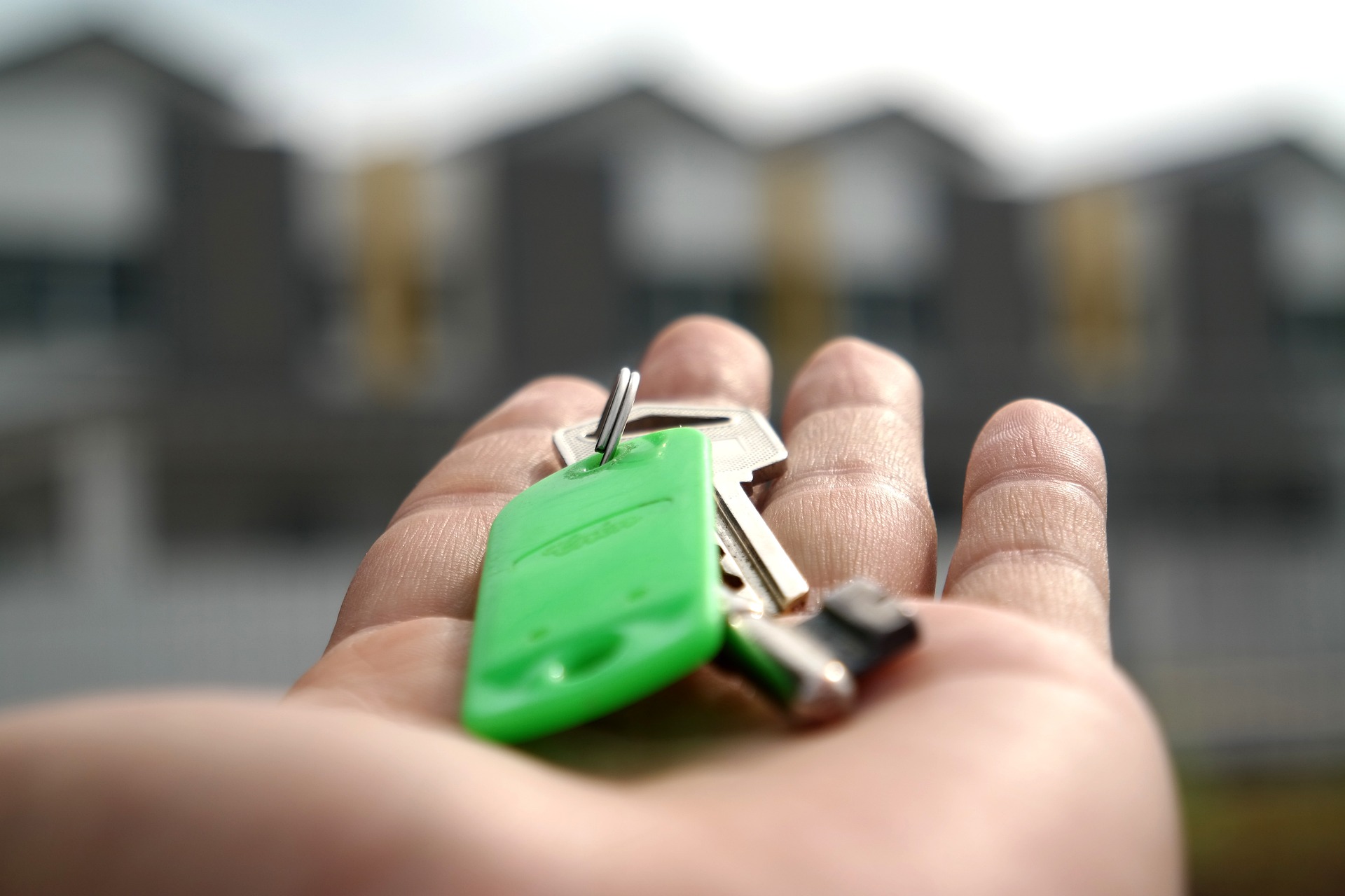 An image showing a hand outstretched with keys and a green keyring attached to it.