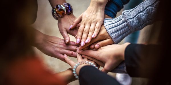 A group of people placing hands on top of each other's in a circle.