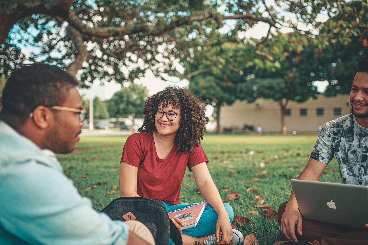 Image showing thee students talking in a grassy area