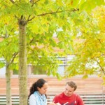Two postgraduate students sitting under tree on Jubilee Campus
