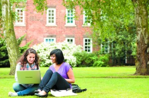 Two female students sitting with laptop outside