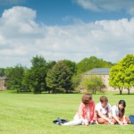 Undergraduate students relaxing on The Downs in front of halls of residence, University park