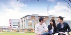 Three postgraduate students studying in front of Business School North, Jubilee campus