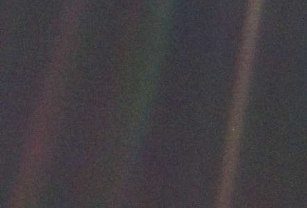 An image of the earth taken by Voyager 1. Due to Voyager's distance, the earth is just a tiny white dot in the centre of one of three scattered rays of light.