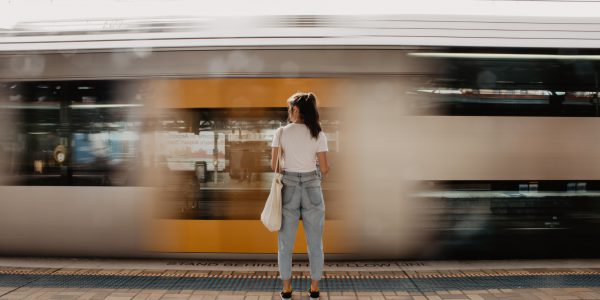 Woman stands on a platform in front of fast moving train.