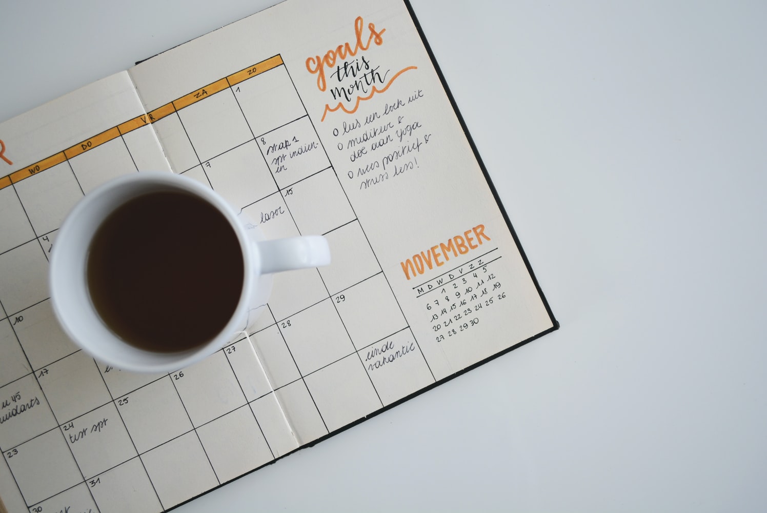 A mug of coffee sitting on top a planner.