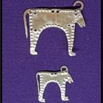 Gold animal-shaped jewellery, possible the shape of a cow, on a purple velvet backdrop