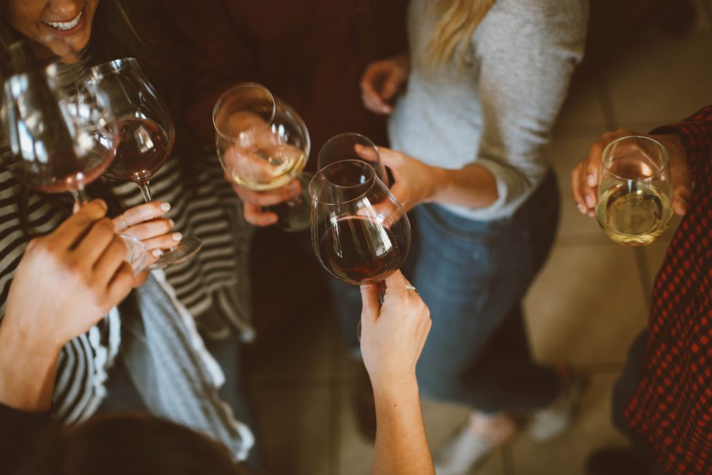 A group of people stand in a circle and cheers their wine glasses
