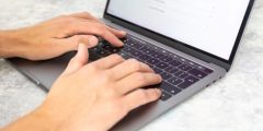 A pair of hands types on a laptop computer